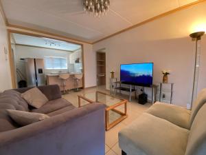 Una sala de estar con dos sofás y un televisor de pantalla plana. en Siena Sun Apartment 6 with water reserve, en Midrand