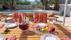een houten tafel met glazen wijn en fruit erop bij NIOS Luxury House in Vathi