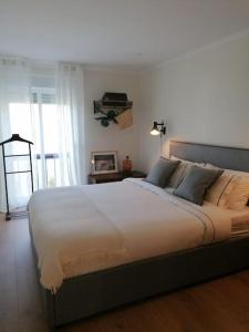 - une chambre avec un grand lit et des draps blancs dans l'établissement Amor a mar, à Sesimbra