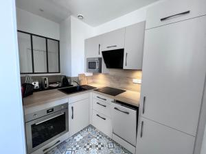a white kitchen with a sink and a refrigerator at La Bulle Dorée in Épernay +18 photos