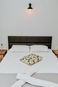 a white bed with a checkered pillow on it at Pia Butik Otel Sığacık in İzmir