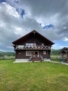 ein großes Holzhaus mit einem Grasfeld davor in der Unterkunft Кришталеві вершини in Worochta