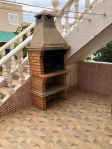 un horno de ladrillo en un patio bajo una escalera en bungalows Santa Pola, en Gran Alacant