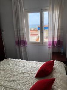 1 cama con 2 almohadas rojas frente a una ventana en bungalows Santa Pola, en Gran Alacant