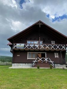una gran casa de madera con un campo verde delante de ella en Кришталеві вершини, en Vorokhta