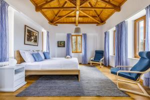 Sunshine Pool Villa near the Sea في سكوبيلوس تاون: غرفة نوم بسرير ابيض وكراسي زرقاء