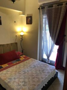 a bedroom with a bed and a window with curtains at vintage apartment with port view in Chios