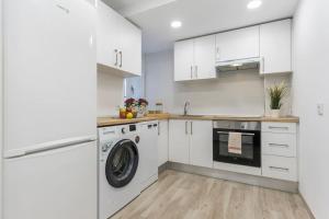 eine Küche mit weißen Schränken und einer Waschmaschine und einem Trockner in der Unterkunft Apartamento Marqués de Urquijo in Gijón + 20 Fotos