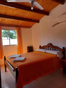 1 dormitorio con 1 cama grande de color naranja y ventana en Mi Media Naranja en Mina Clavero