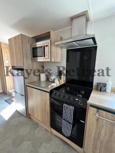 cocina con fogones negros y microondas en Kayes Retreat Three bed caravan Newquay Bay Resort Quieter area of park en Newquay