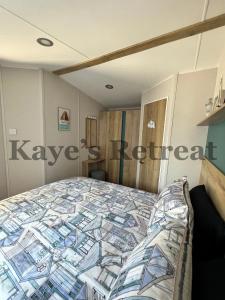 ニューキーにあるKayes Retreat Three bed caravan Newquay Bay Resort Quieter area of parkのベッドルーム(カラフルなキルトのベッド付)