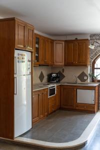 a kitchen with wooden cabinets and a white refrigerator at Sotiria house apartment sea view lovely garden in Ierissos