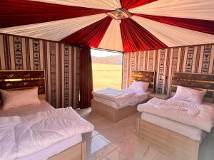 3 łóżka w pokoju z dużym namiotem w obiekcie Wadi Rum Sand Camp w mieście Disah