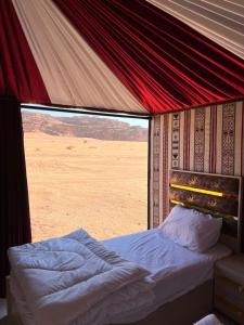 łóżko w namiocie z widokiem na pustynię w obiekcie Wadi Rum Sand Camp w mieście Disah