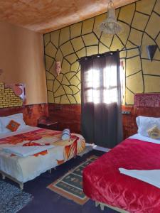 a room with two beds and a window in it at Riad Tigmi du Soleil in Aït Ben Haddou