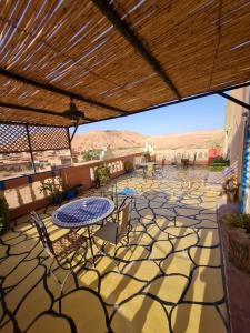 a patio with tables and chairs and mountains in the background at Riad Tigmi du Soleil in Aït Ben Haddou