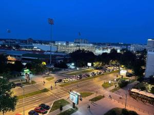 a city with cars parked on a street at night at Promenada Apartment in Novi Sad