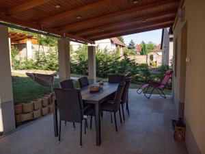 eine Terrasse mit einem Holztisch und Stühlen darauf in der Unterkunft Martour-ház in Fonyód