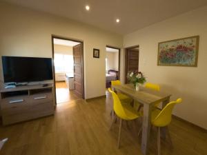 a living room with a dining room table and yellow chairs at Martour-ház in Fonyód