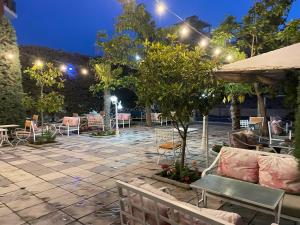 un patio con sillas, mesas y luces por la noche en Sanremo Hotel Restorant, en Durrës