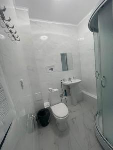 a white bathroom with a toilet and a sink at Мунайшы in Atyraū