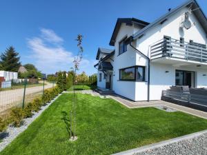 una casa blanca con un patio verde en Cichy Domek - Podgrzewany Basen, Parking, Aneks Kuchenny, en Karwia