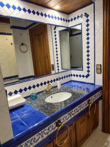 uma casa de banho azul e branca com um lavatório e espelhos em Can Vila Rupit em Rupit
