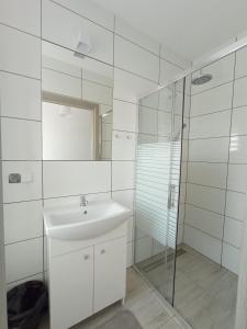 a white bathroom with a sink and a shower at Wynajem pokoi in Władysławowo