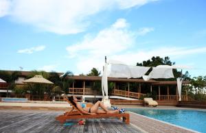a woman laying on a bench next to a pool at Boffo Resort in Loon