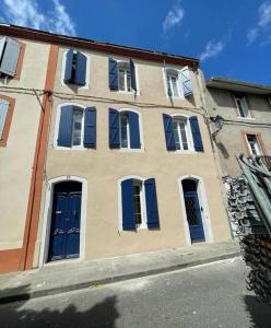 un bâtiment avec des portes et des fenêtres bleues dans une rue dans l'établissement Escapade détente au cœur de Pamiers, à Pamiers