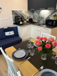 una mesa de comedor con rosas rojas en un jarrón en Apartament przy morzu W22, en Rowy