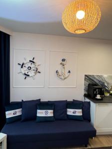 - un salon avec un canapé bleu et deux photos dans l'établissement Apartament przy morzu W22, à Rowy