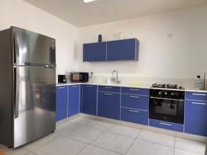 La cuisine est équipée de placards bleus et d'un réfrigérateur en acier inoxydable. dans l'établissement Magdala Infront Sea of Galilee and Mount Harbel, à Migdal