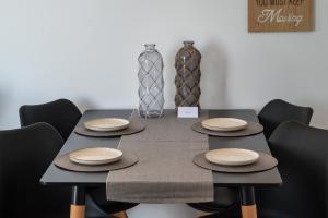 a black table with black chairs and plates on it at Anzuelo Apartments in Megalochori