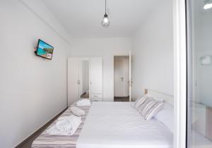 a bedroom with white walls and a bed with white sheets at Anzuelo Apartments in Megalochori