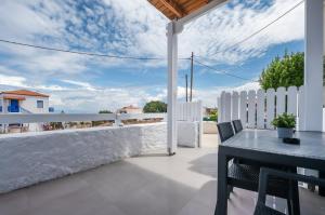 a patio with a table and chairs and a white fence at Anzuelo Apartments in Megalochori