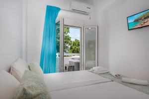 a white bedroom with a large bed and a window at Anzuelo Apartments in Megalochori