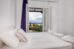 a white bedroom with a large bed and a window at Anzuelo Apartments in Megalochori