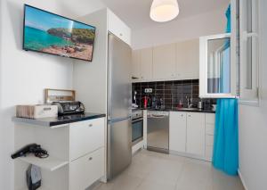 a kitchen with white cabinets and a tv on the wall at Anzuelo Apartments in Megalochori