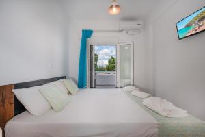 a bedroom with a large white bed with a window at Anzuelo Apartments in Megalochori