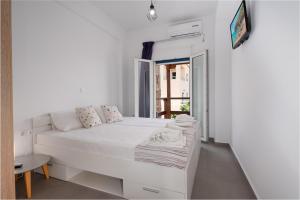 a white bedroom with a white bed and a window at Anzuelo Apartments in Megalochori