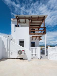 a white house with a fence and a fan at Anzuelo Apartments in Megalochori