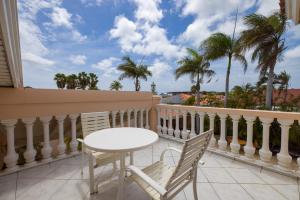 balcón con mesa, sillas y palmeras en Bubali Villa, en Palm-Eagle Beach