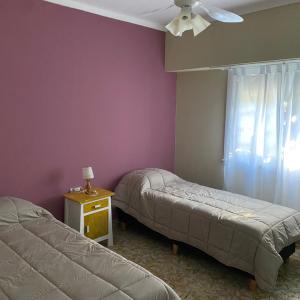 a bedroom with two beds and a ceiling fan at Hosteria Tobago in Necochea