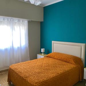a bedroom with a orange bed and a blue wall at Hosteria Tobago in Necochea