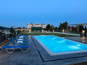 a row of lounge chairs next to a swimming pool at Athens Countryside resort with pool in Pallíni