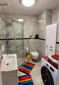 a bathroom with a shower and a sink and a washing machine at Apartament Comfort Del Mar II Kolobrzeg in Kołobrzeg