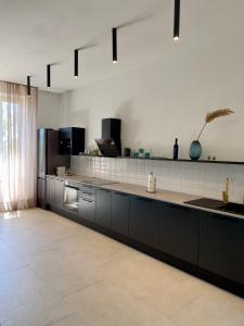 a kitchen with black cabinets and a white wall at Rosetta Suite in Novi Vinodolski