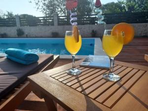two glasses of orange juice on a table next to a pool at Apartment Karla SNB in Lozovac