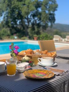 a table with a breakfast of bread and orange juice at Hôtel La Boulangerie in Grimaud